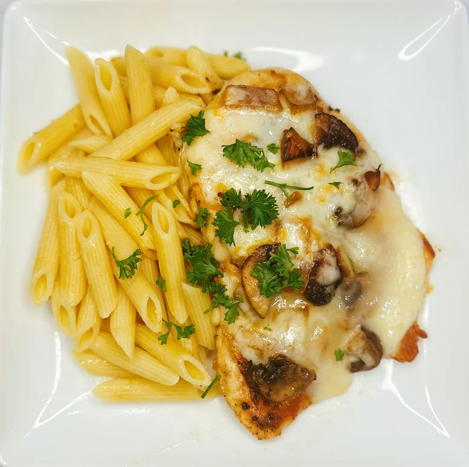 smothered chicken breast topped with melted cheese and onions served with pasta