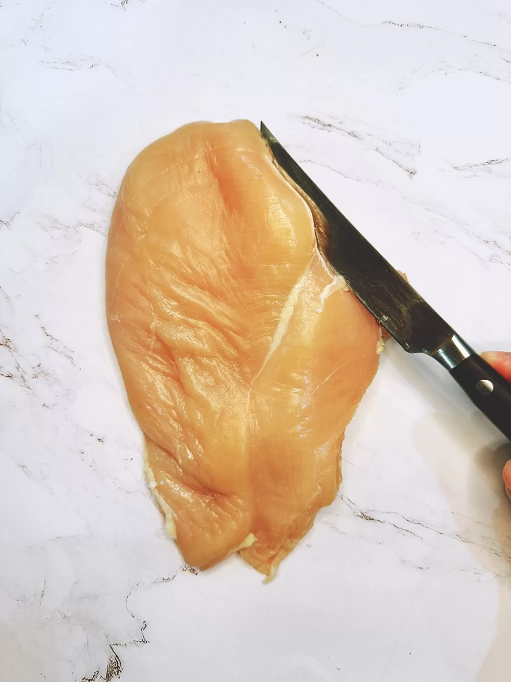 chicken breast being butterfly sliced