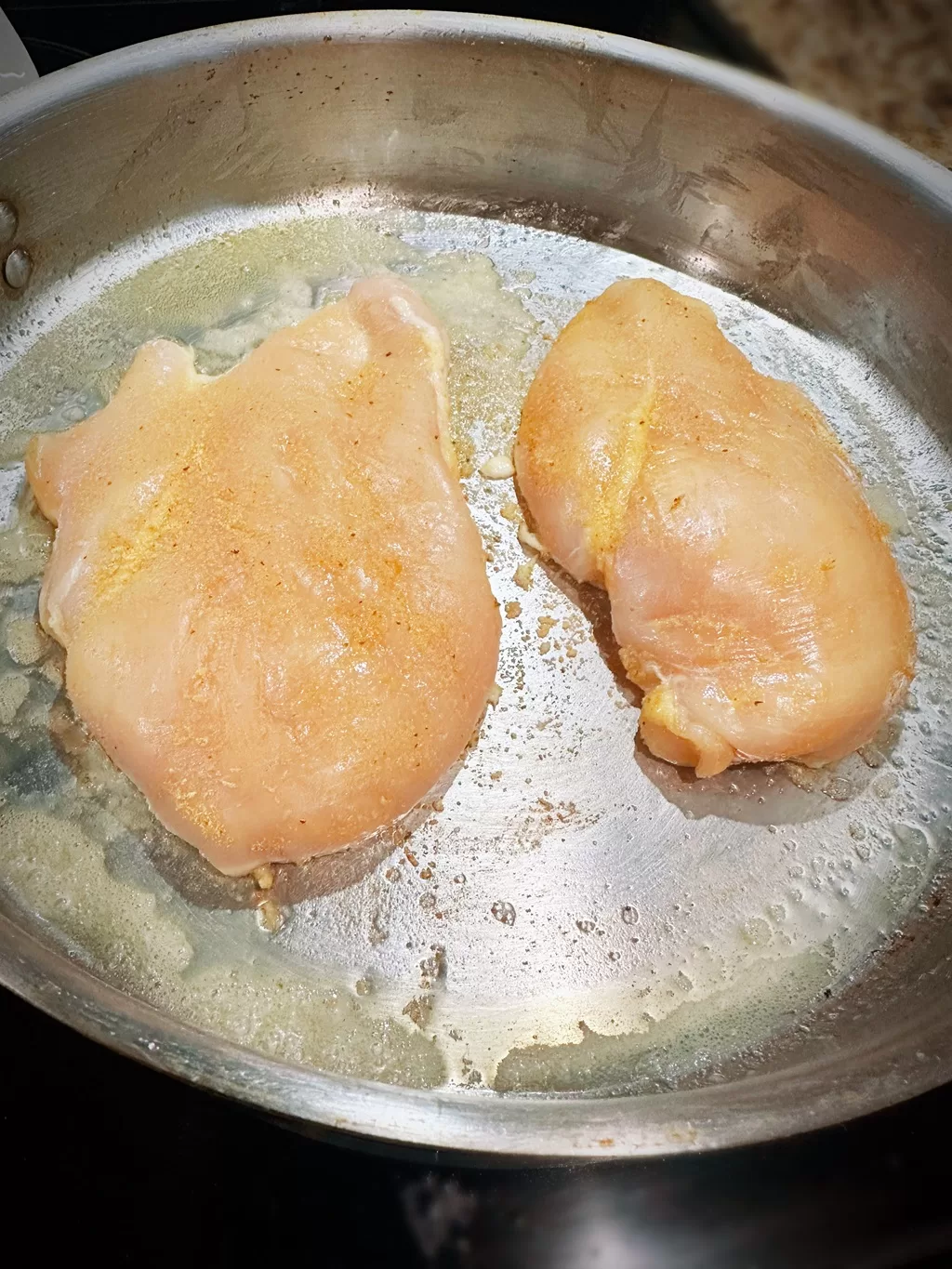 raw chicken searing in a pan