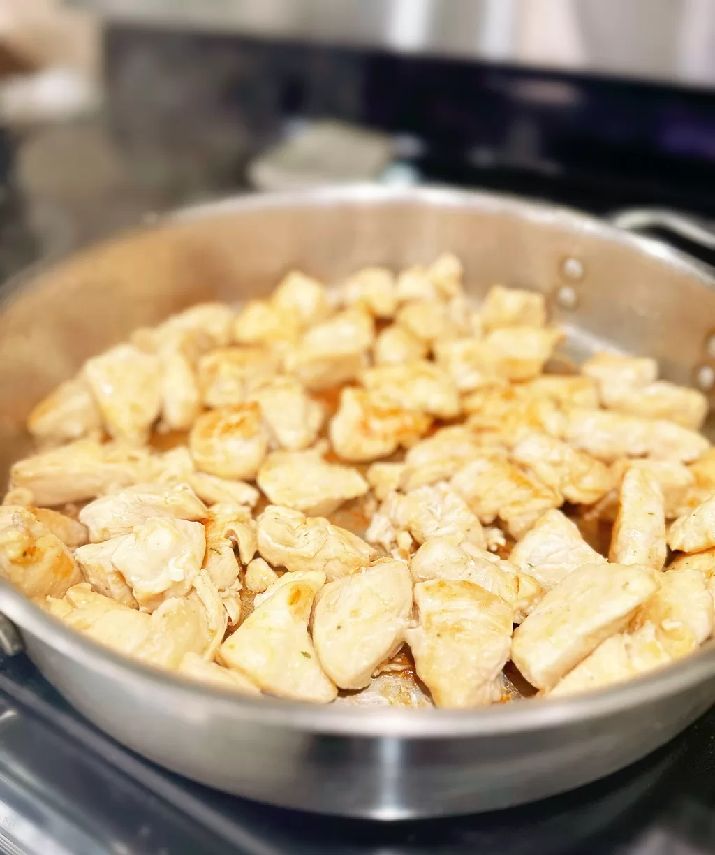 cubes of chicken cooking in pan