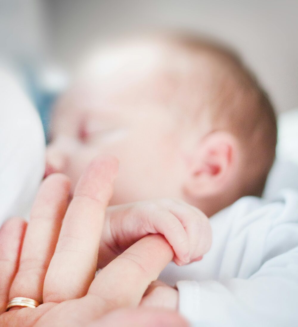 baby sleeping holding parents hand