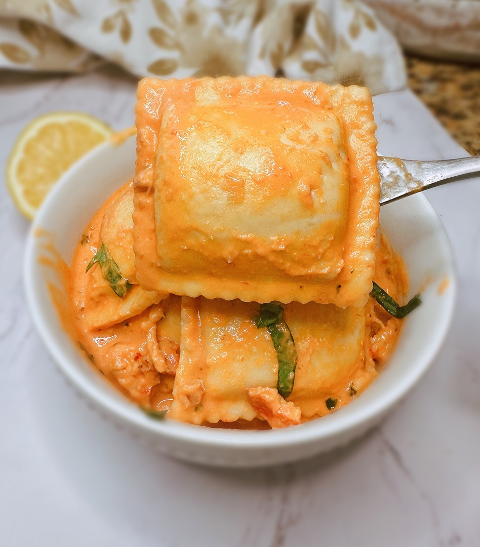 closeup of ravioli covered in pink lobster sauce on a fork