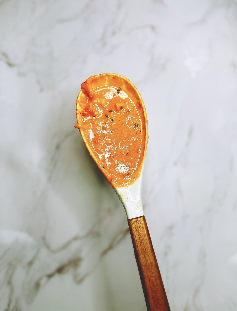 lobster ravioli sauce in a white serving spoon
