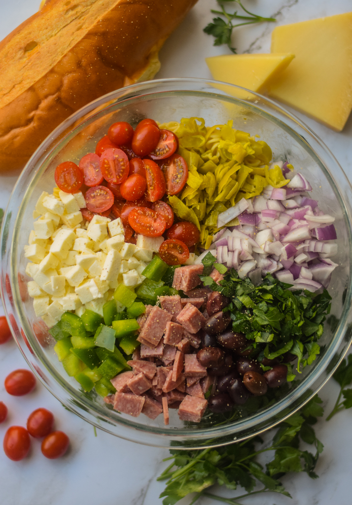italian pasta salad ingredients in a glass bowl before being mixed