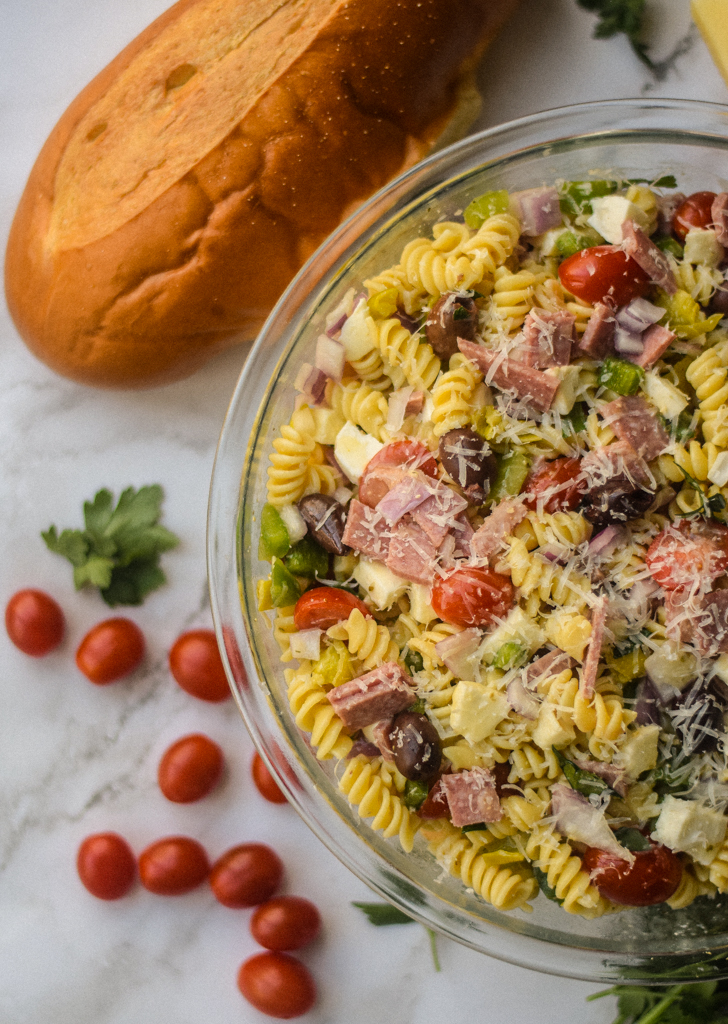 itlalian pasta salad in glass bowl with italian bread and cherry tomatoes