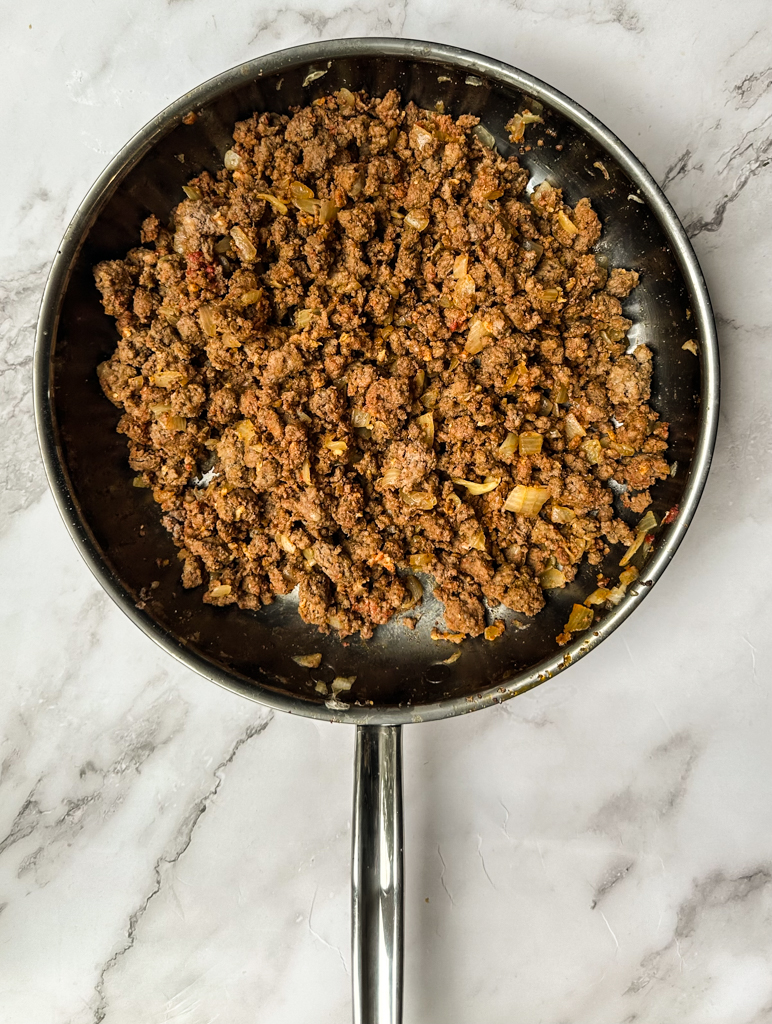 seasoned ground beef cooked in a frying pan with onions