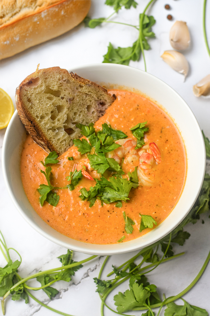 closeup of crab and shrimp seafood bisque in a bowl with bread and fresh parsley