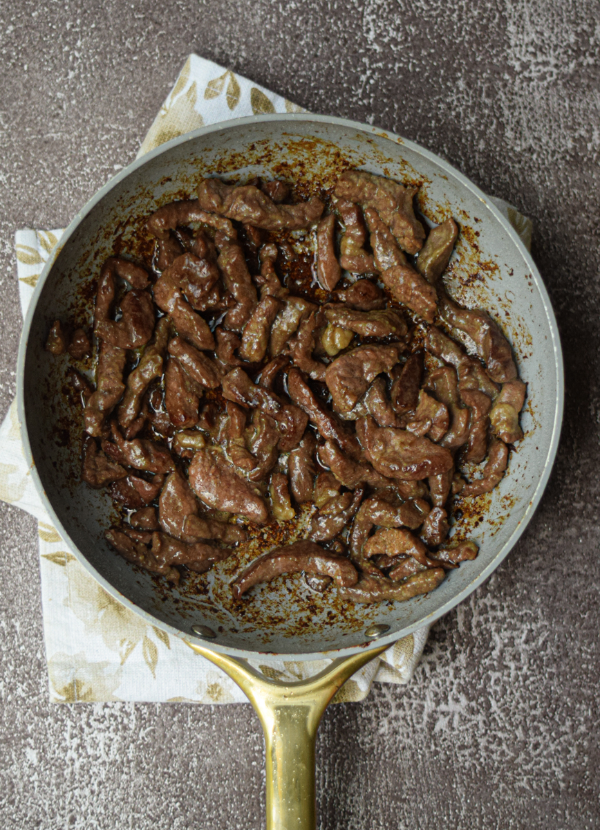 flank steak searing in a white pan