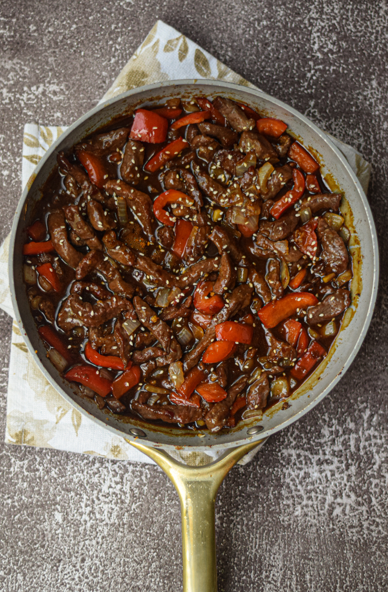 Beijing beef in a pan with red bell peppers