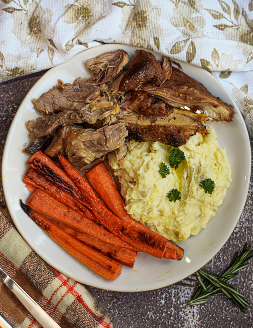 apple cider roasted pork shoulder plated with mashed potatoes and roasted carrots