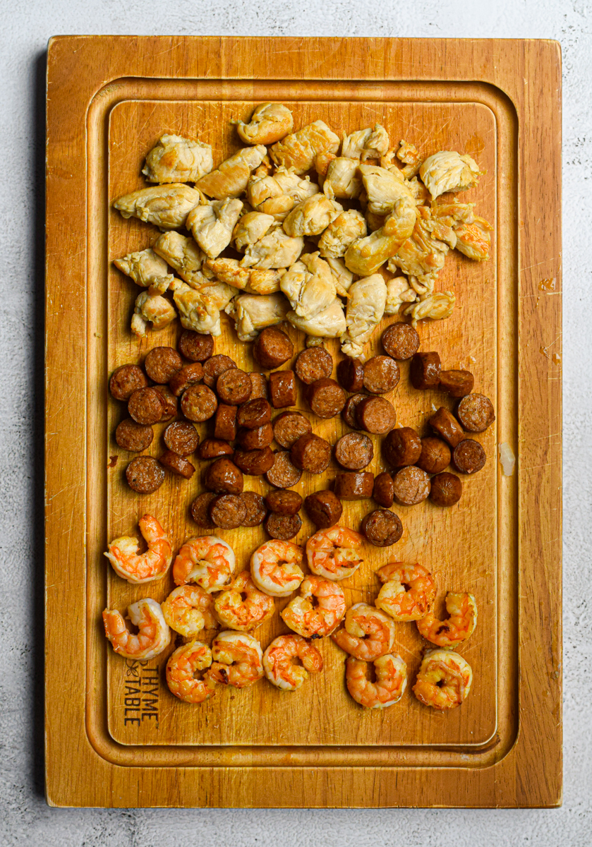 chicken, andouille sausage, and shrimp on a wooden cutting board