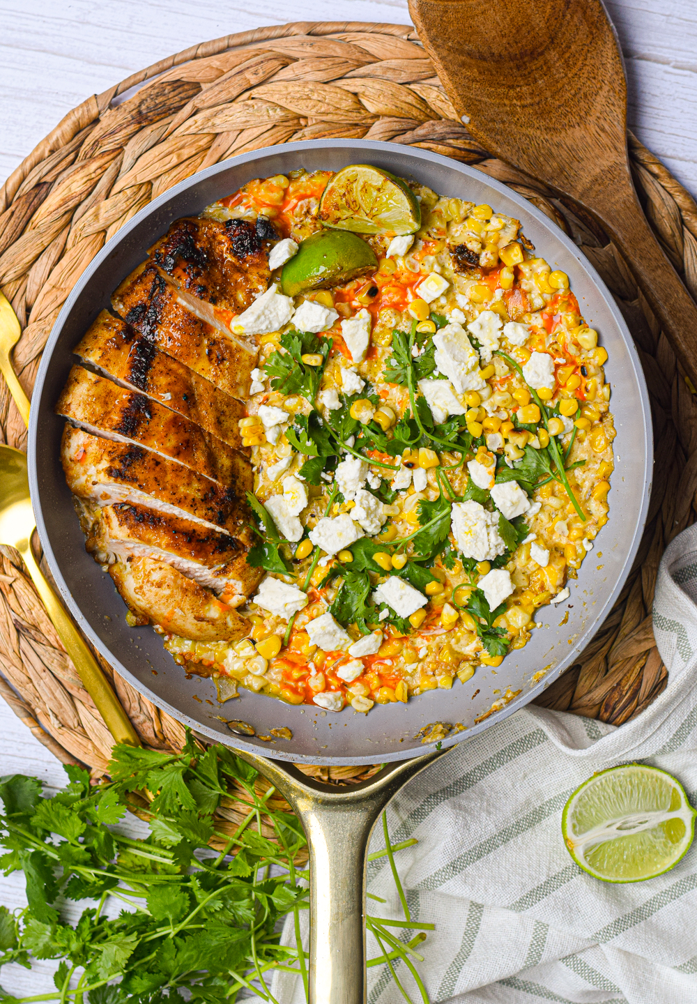 Mexican Street Corn Chicken Skillet surrounded by fresh herbs in a white frying pan