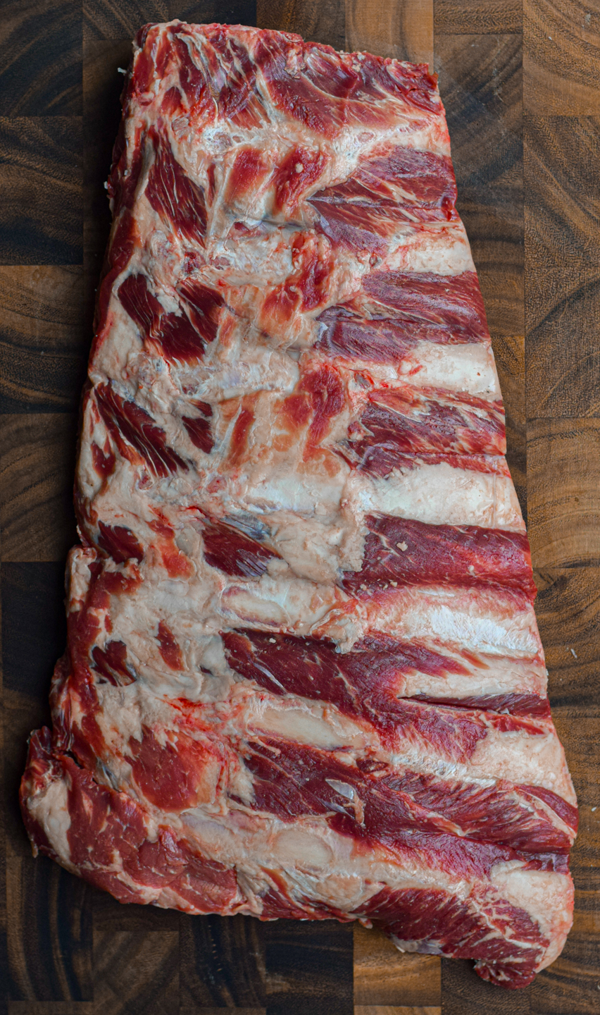 raw beef back ribs on a wooden chopping board
