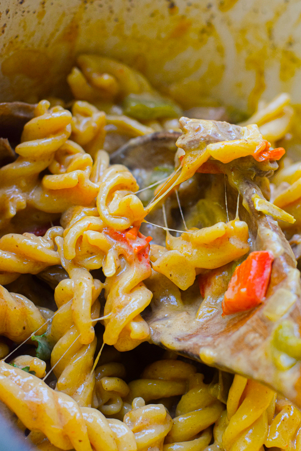 philly cheesesteak pasta closeup on a wooden spoon