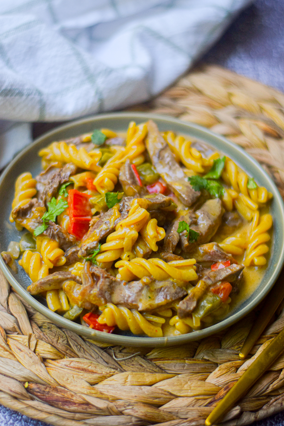 philly cheesesteak pasta on a green plate