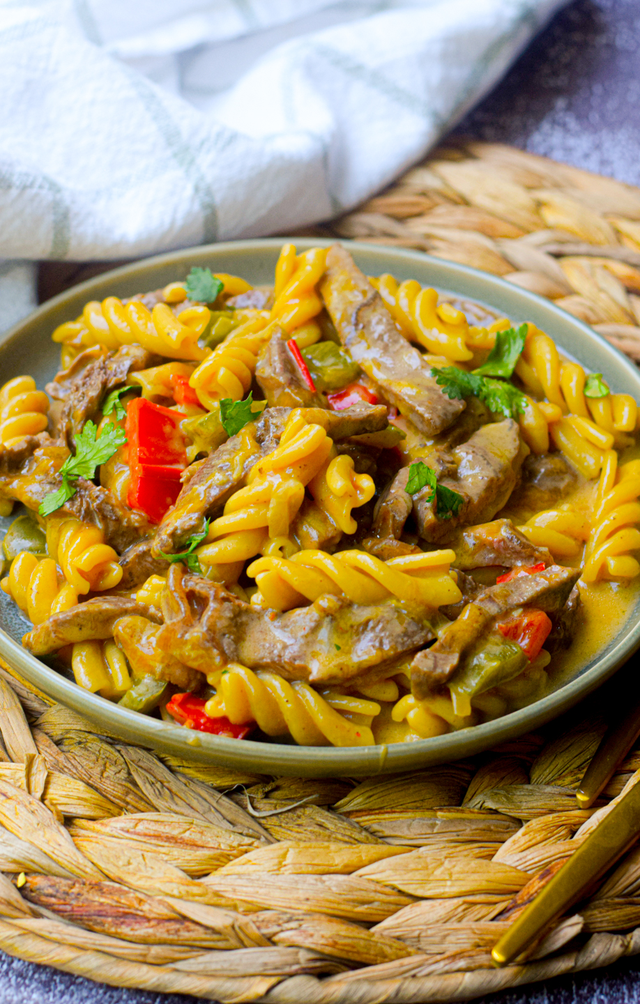 philly cheesesteak pasta on a green plate