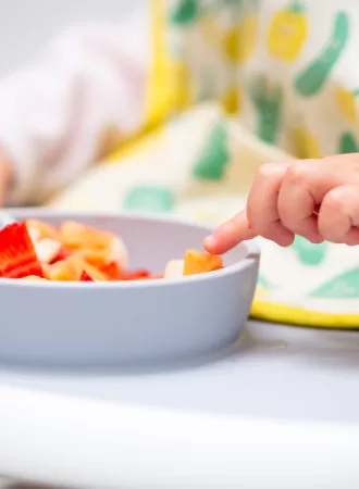 Macro Close up of Baby Hand with a Piece of Fruits Sitting in Child's Chair Kid Eating Healthy Food