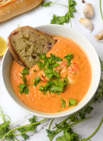 closeup of crab and shrimp seafood bisque in a bowl with bread and fresh parsley