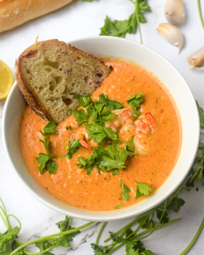 closeup of crab and shrimp seafood bisque in a bowl with bread and fresh parsley